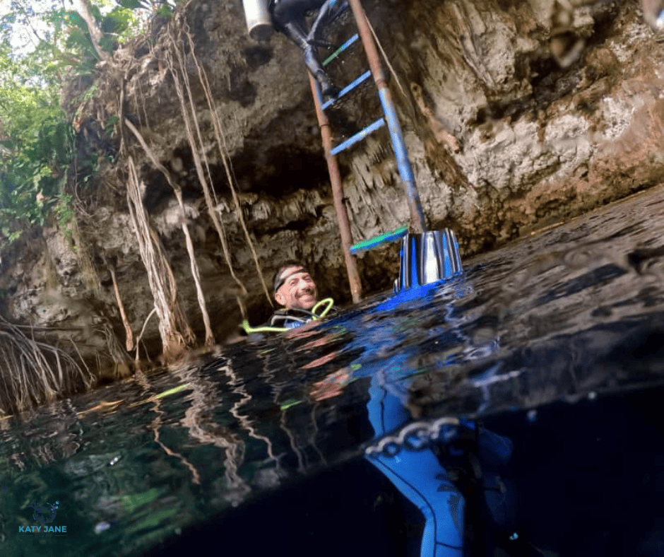 man in water in blue wetsuit in cavern in jungle