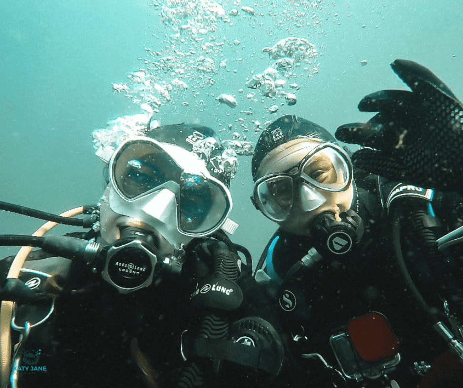 two divers taking selfie underwater with white mask and green background