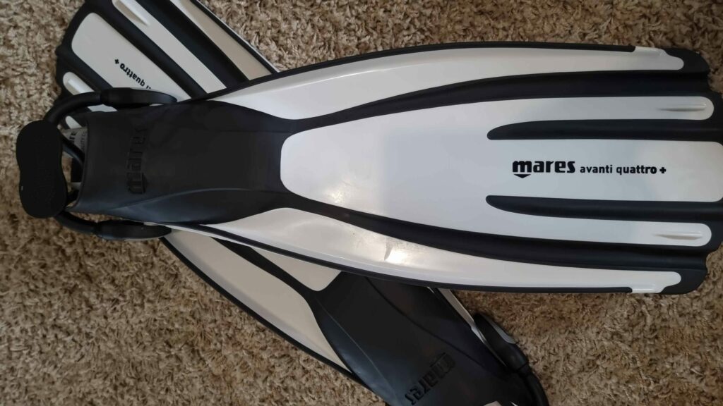 white and black scuba diving fins on floor