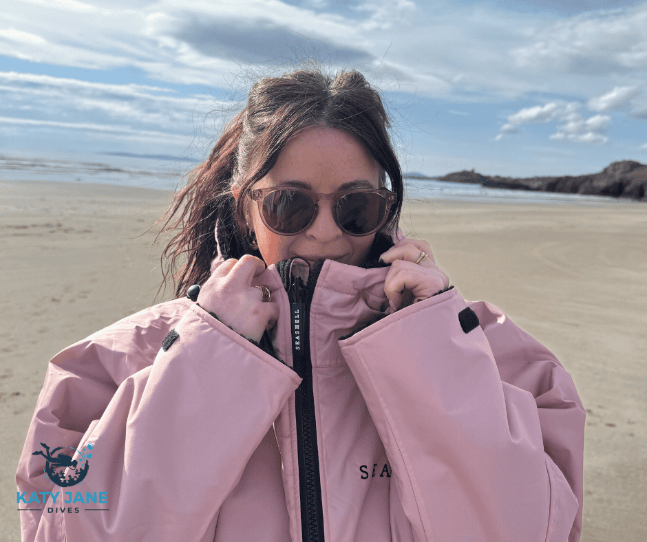 person standing on beach in pink changing robe facing camera