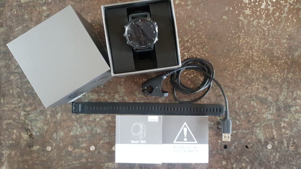 black watch with grey box and leads on a brown table