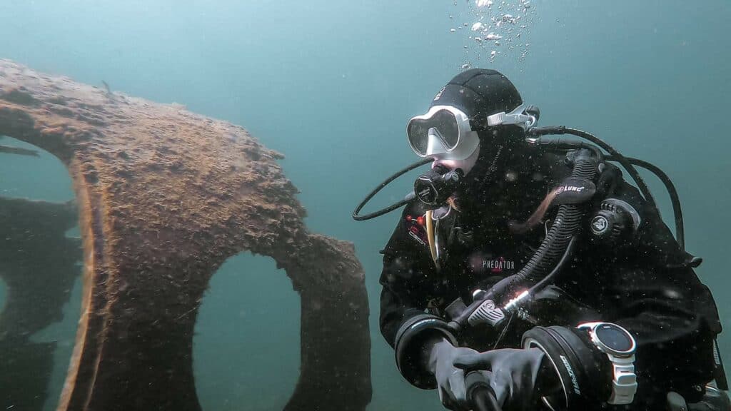 Scuba diver underwater in blue water next to plane wreck