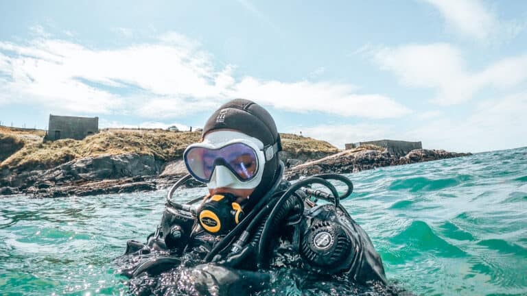Diver at surface in turquoise water with white mask and blue skies