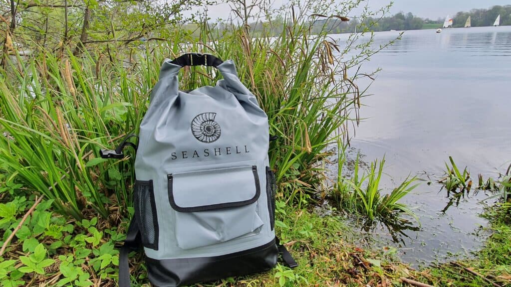 Seashell drybag front by water and grass