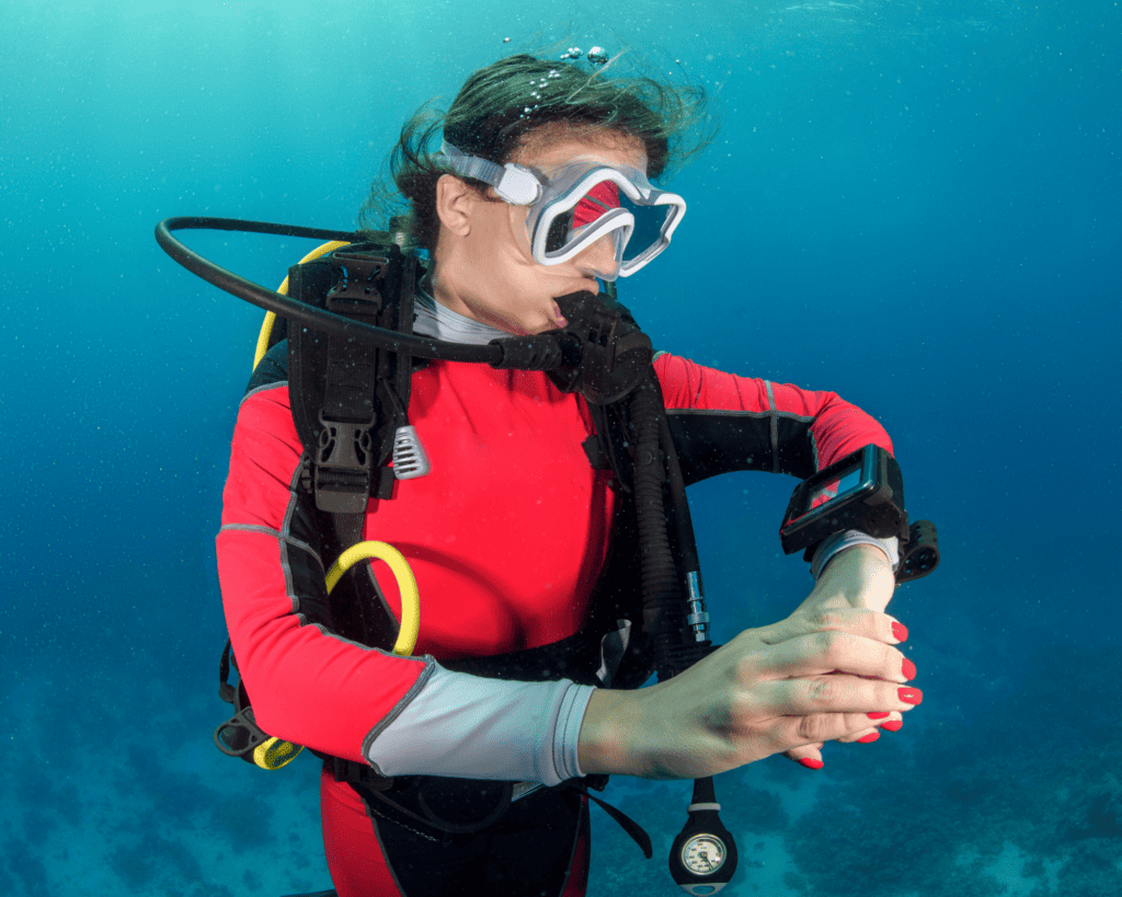 Scuba girl checking dive computer underwater