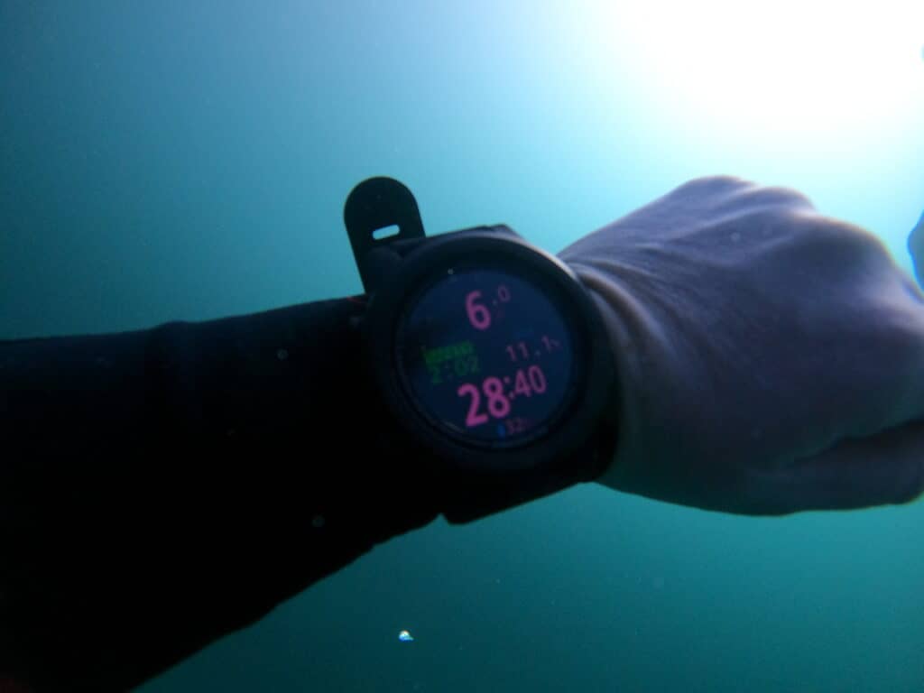 dive computer on arm underwater with blue background