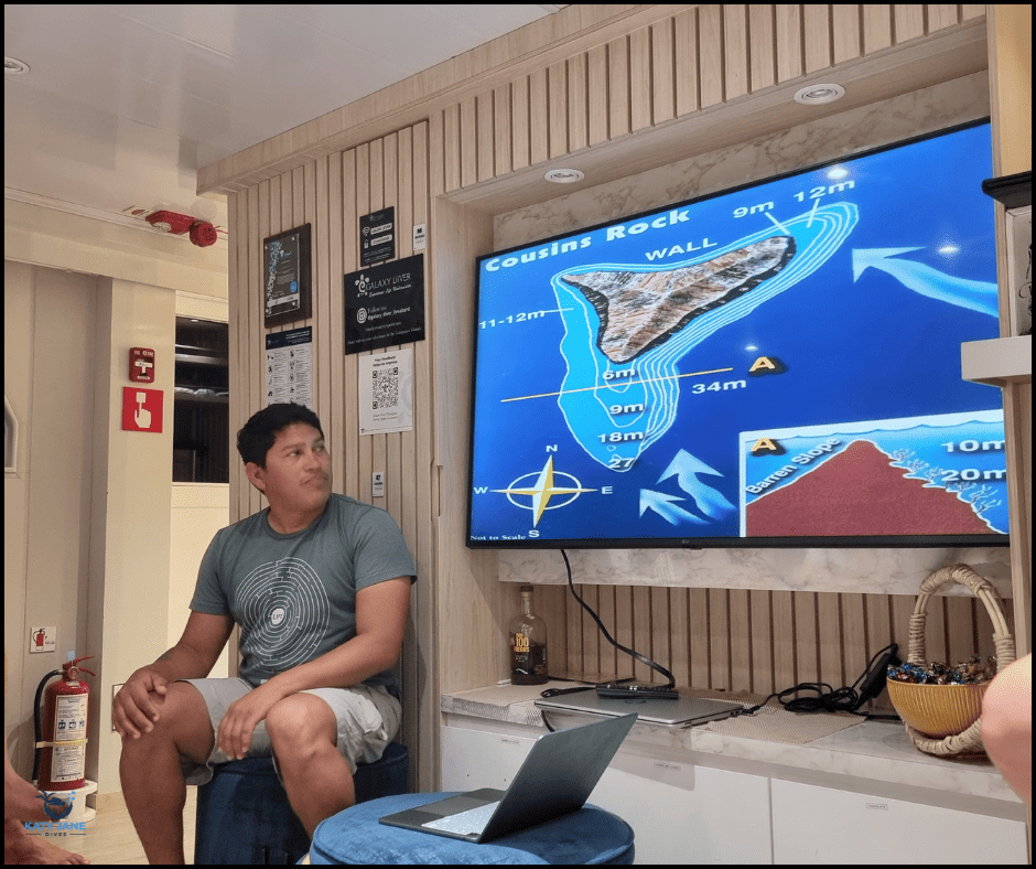 person talking in front of a tv screen showing a map of a dive site