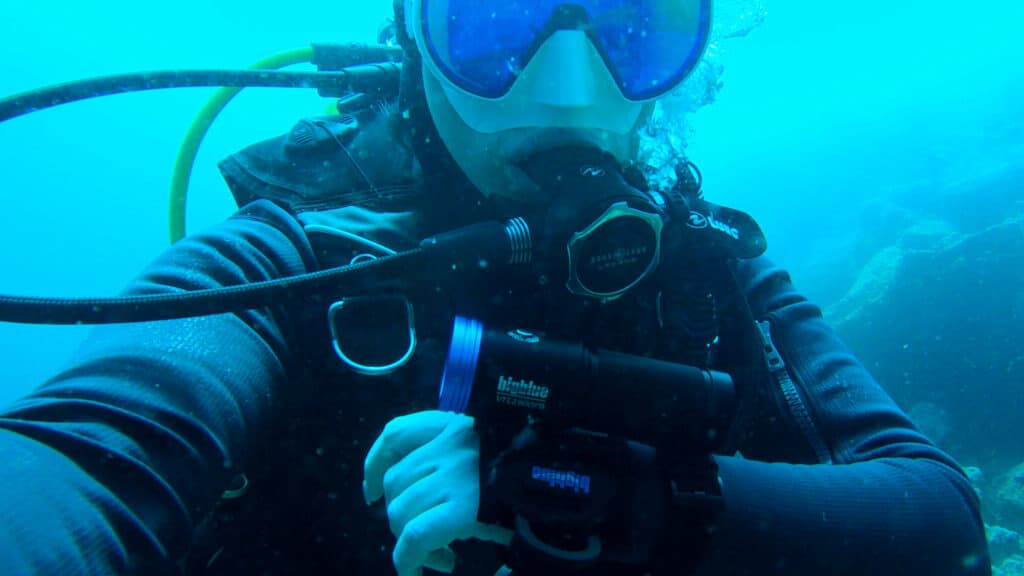 scubadiver underwater close up with dive torch on hand