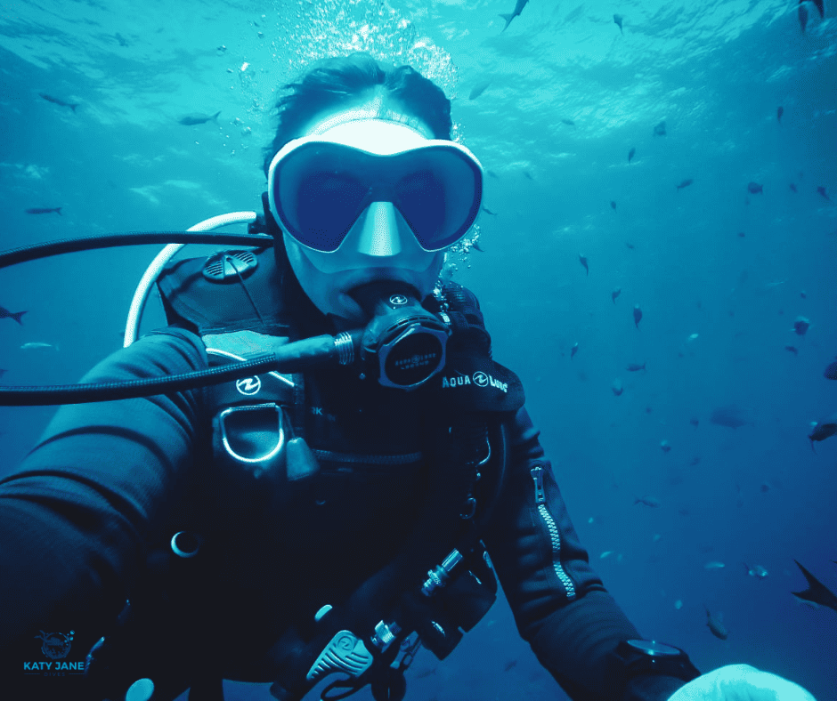 diver with white mask underwater with fish around