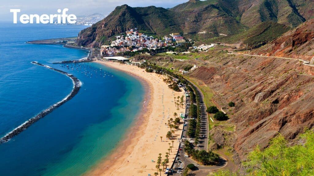 Arial photo of tenerife coastline with blue water and golden beach and mountains